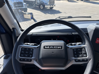 Mack PR64T76H truck steering wheel with mounted control pads; dashboard visible through windshield.