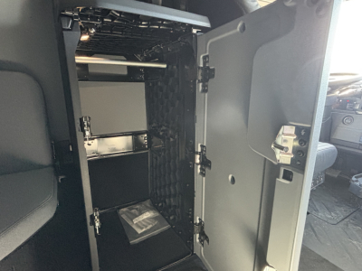 Truck cab interior showing a storage cabinet with shelves and a door open in a Mack PR64T76H sleeper cab.