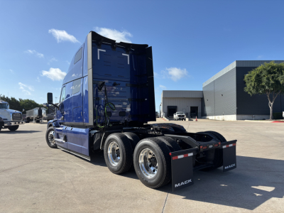 Mack PR64T76H truck tractor rear view showing triple axle configuration and blue cab with high roof.