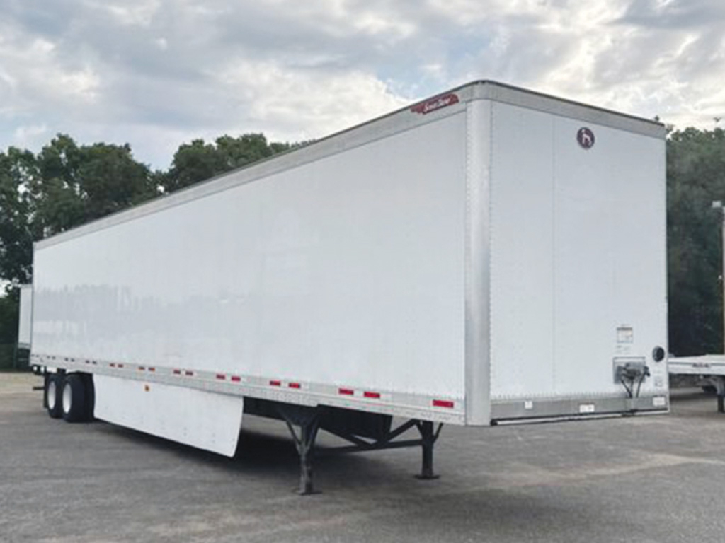 Trailer side view showing a white 2020 Great Dane Champion SE enclosed trailer with tandem rear wheels, front hitch, and loading ramp area.