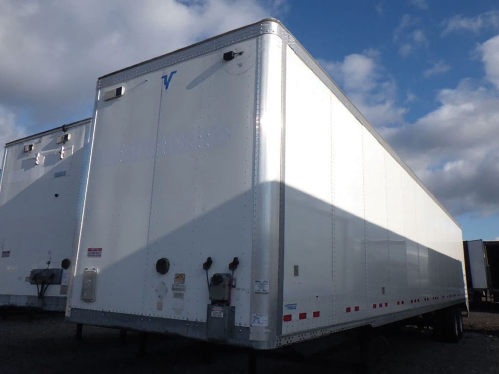 Trailer side and rear of a white Vanguard plate van with VIN HM704492 and stock number 556901, boxed trailer with reflective tape and rear doors.