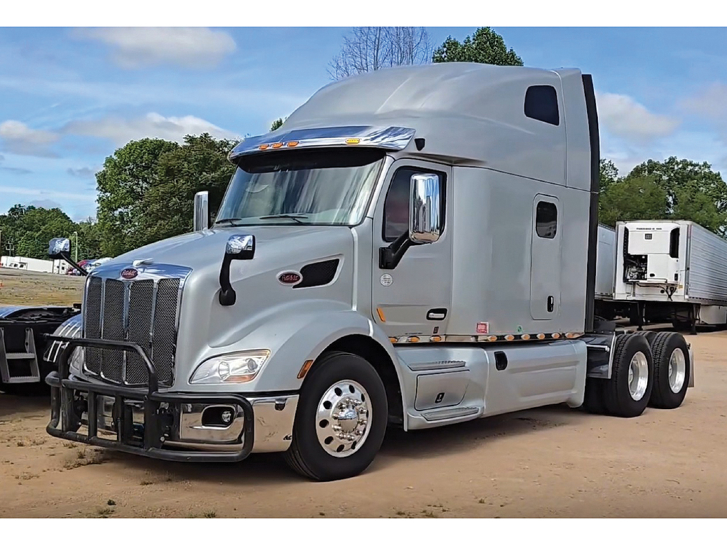 Peterbilt 579 tractor unit side angle showing cabin, grille, chrome bumper guard, and dual rear axles.