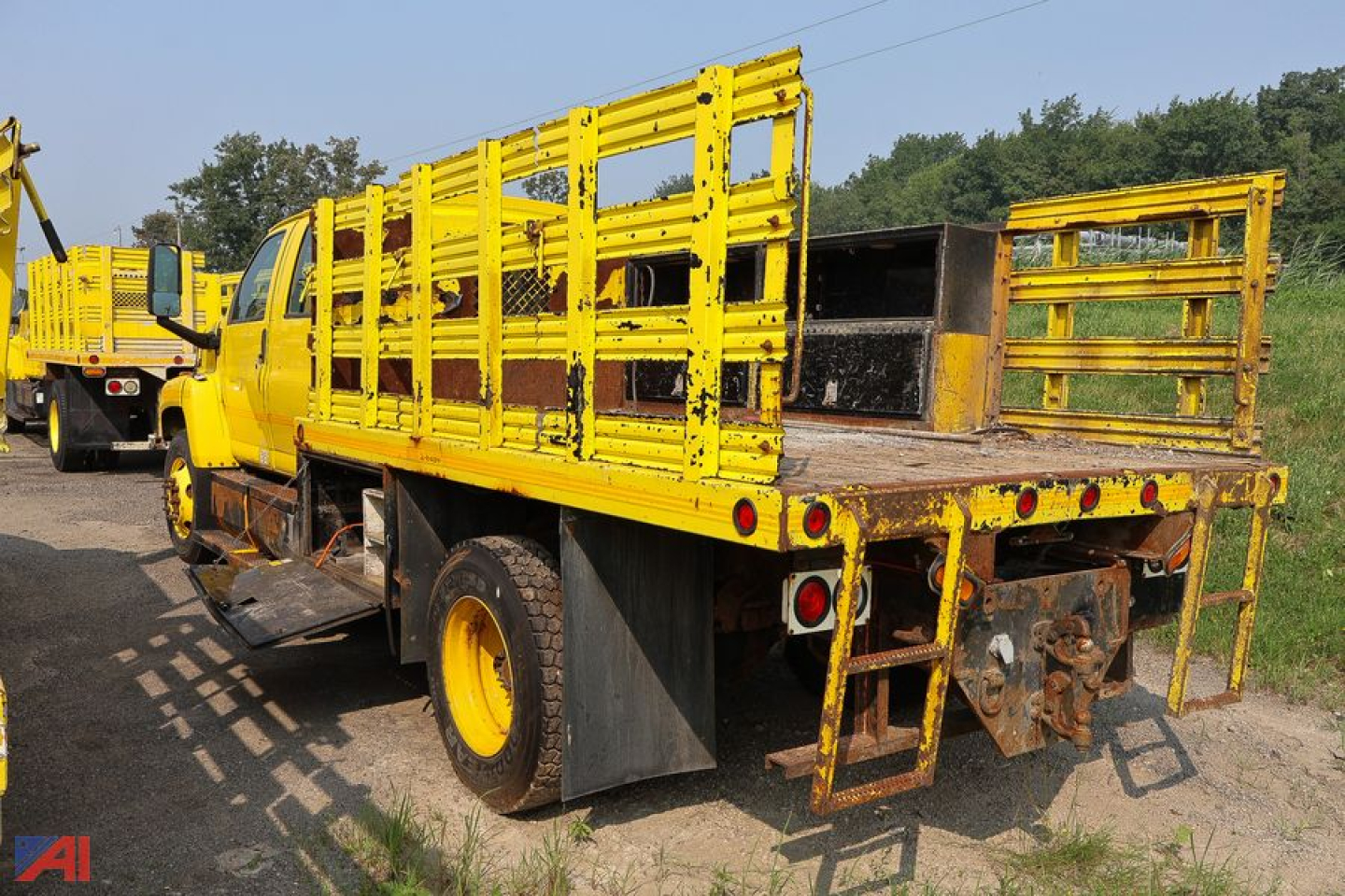 Truck bed with bright yellow stake sides and flatbed rear showing rear gate and hitch.
