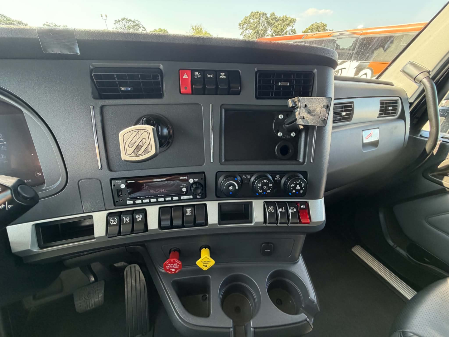Kenworth T680 cab interior dash with steering wheel, center console controls, air vents, and dashboard switches visible.