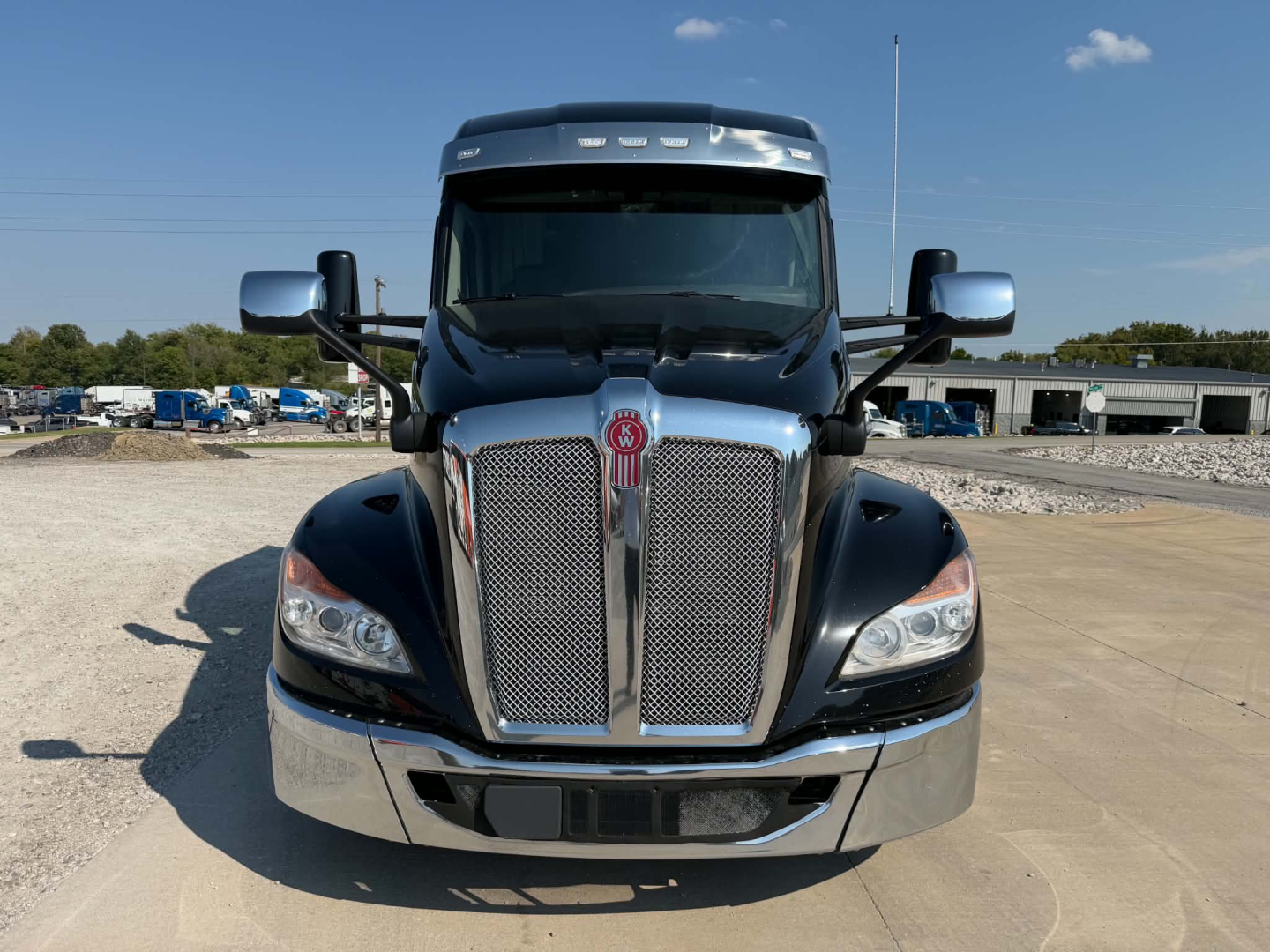 Kenworth T680 front view with large chrome grille and badge, clear windshield, side mirrors visible.