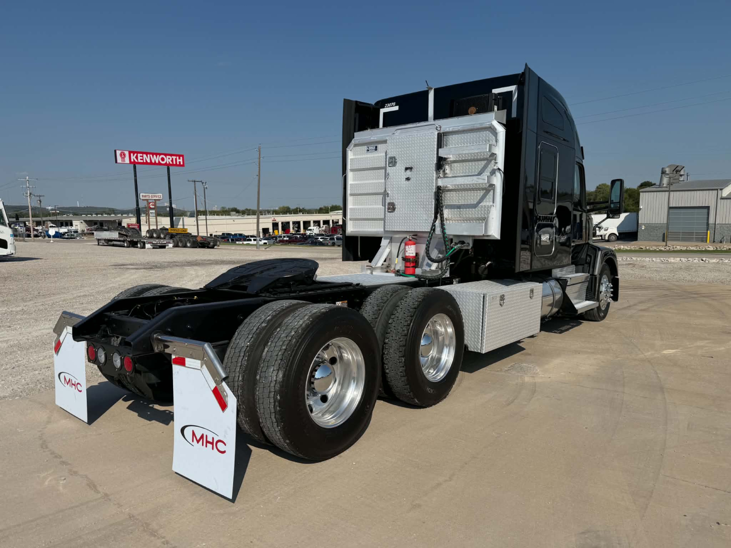 Kenworth T680 tractor rear view showing dual rear axles and aluminum fuel/aluminum-between frame, with mud flaps labeled MHC.