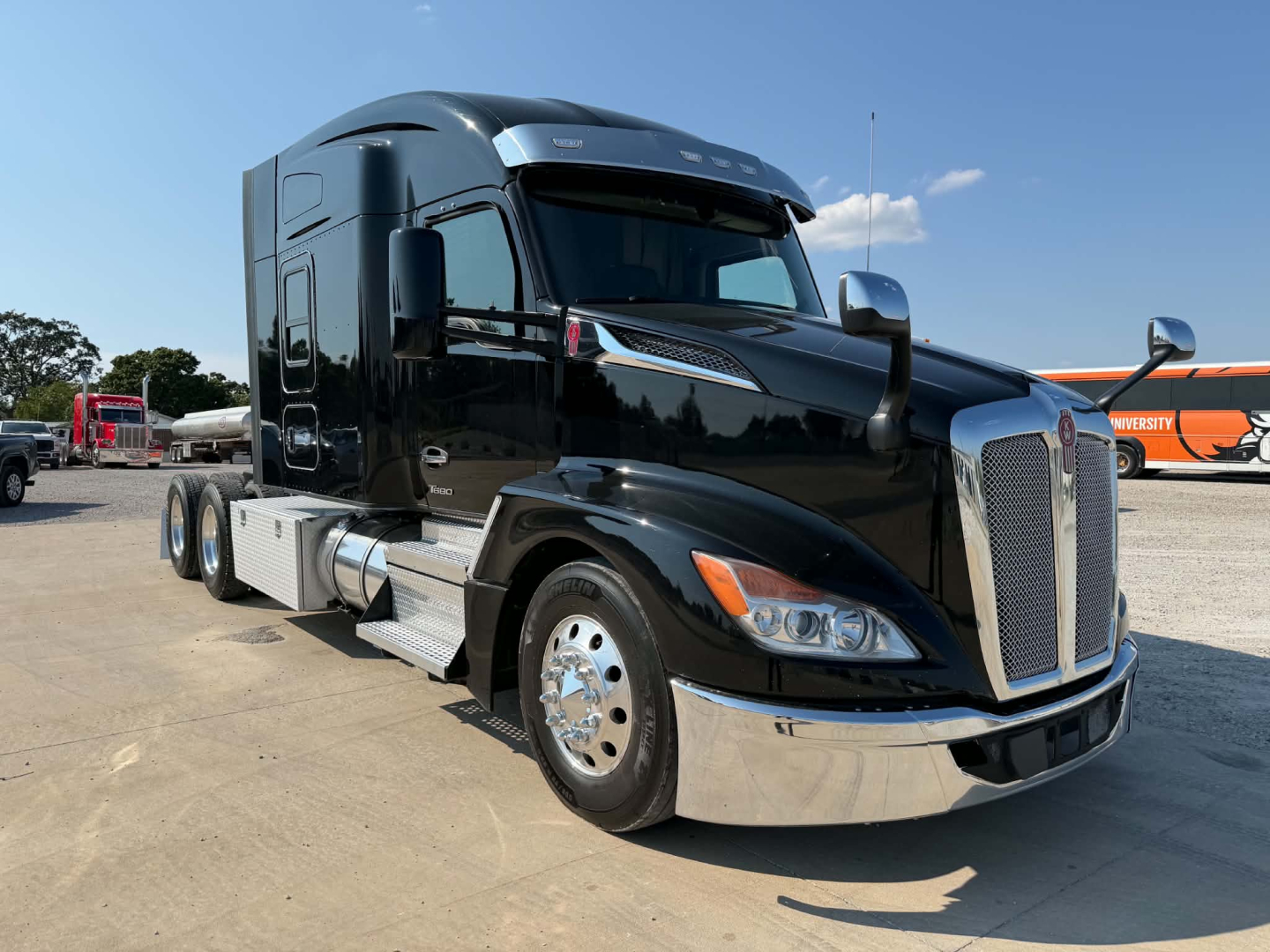 Truck image of a black 2023 Kenworth T680 conventional cab with sleeper, showing chrome front grille, headlights, fuel tanks, and dual rear axles.