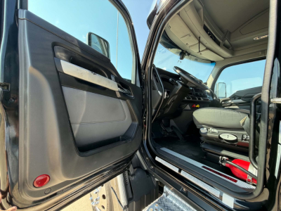 Kenworth T680 cab interior and open driver door showing dashboard and seat area.