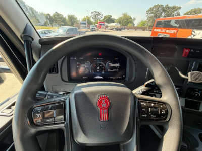 Kenworth T680 interior view showing steering wheel with KW emblem, digital instrument cluster, and dashboard controls.