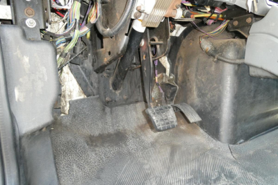 Cab floor and pedals of a 2004 International 4300 showing exposed wiring under dashboard