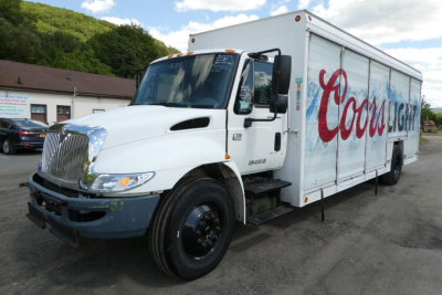 Truck side view showing a white 2004 International 4300 beverage delivery truck with large Coca-Cola Lite graphic on the cargo box.