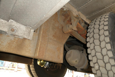 Underneath view of a 2004 International 4300 truck showing suspension, driveshaft, and rear wheel with heavy-duty axle housing.
