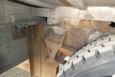 Truck chassis undercarriage showing suspension leaf spring bracket and tire tread. No legible numbers visible.