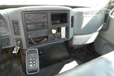 Interior dashboard of a 2004 International 4300 truck showing instrument cluster, radio, climate controls, and an exposed panel with wiring.