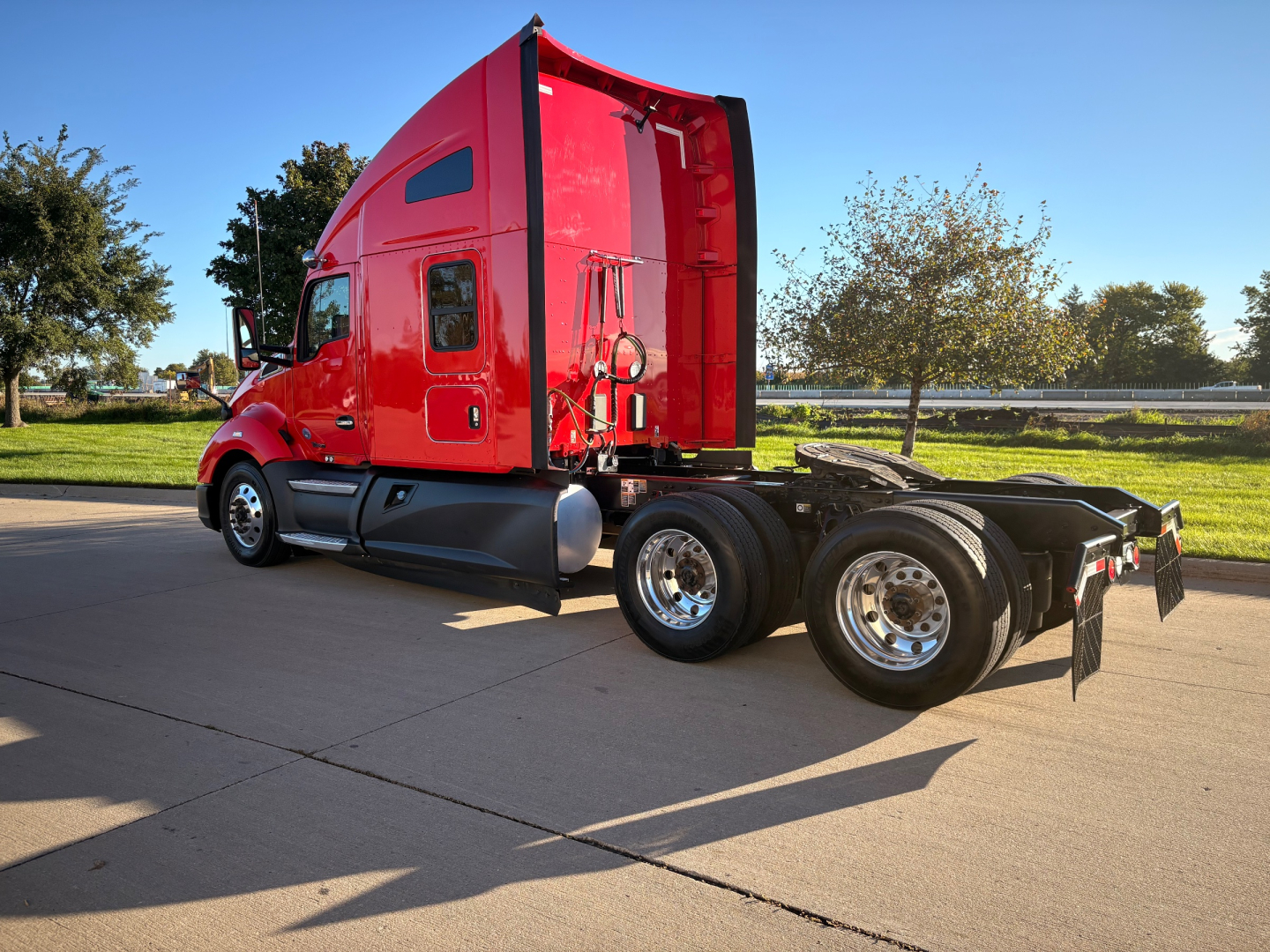 Kenworth T680 conventional sleeper truck side view with red cab and dual rear axles.