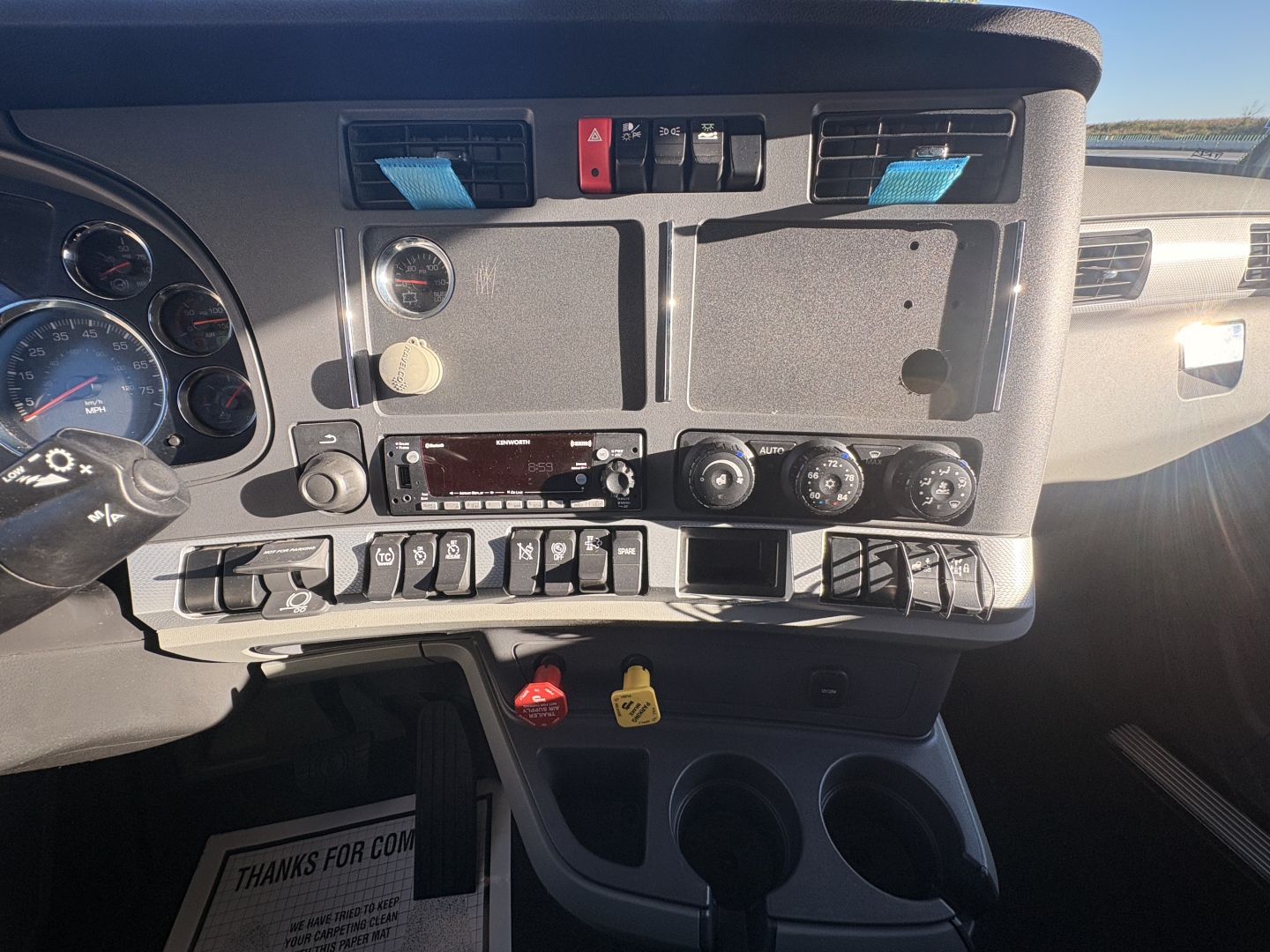 Kenworth T680 truck dash panel with controls, gauges, and cup holders visible.