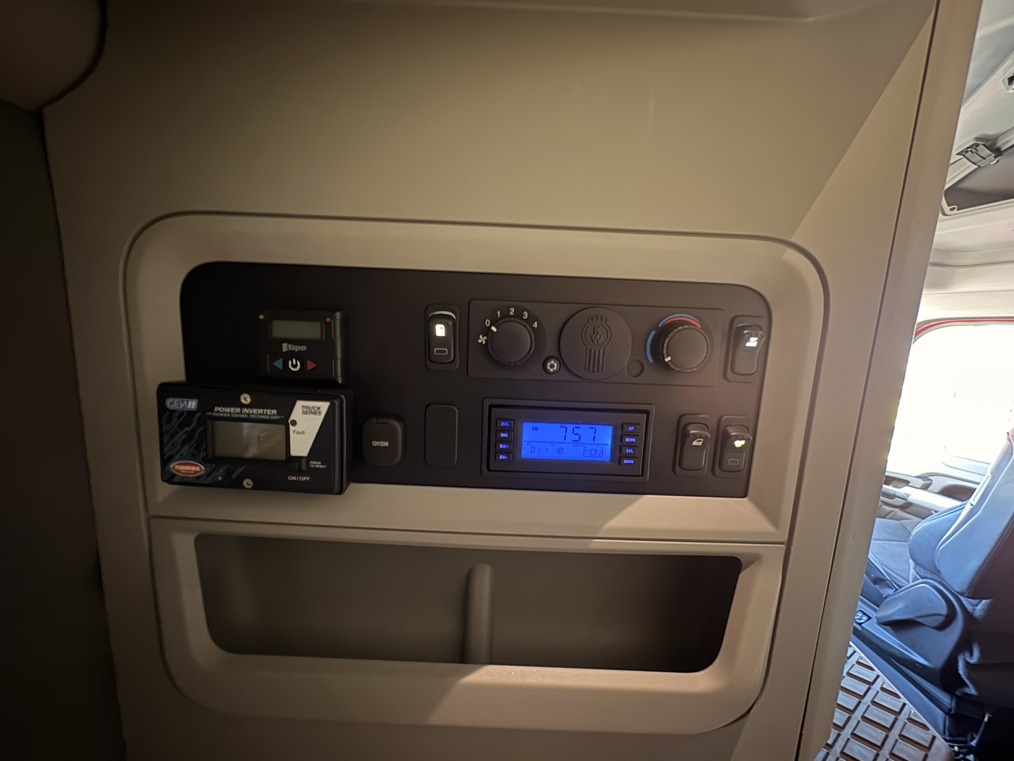 Cabinet panel inside Kenworth T680 dashboard showing controls, multimedia display, and a card reader in the upper left; blue-lit display in the center bottom.
