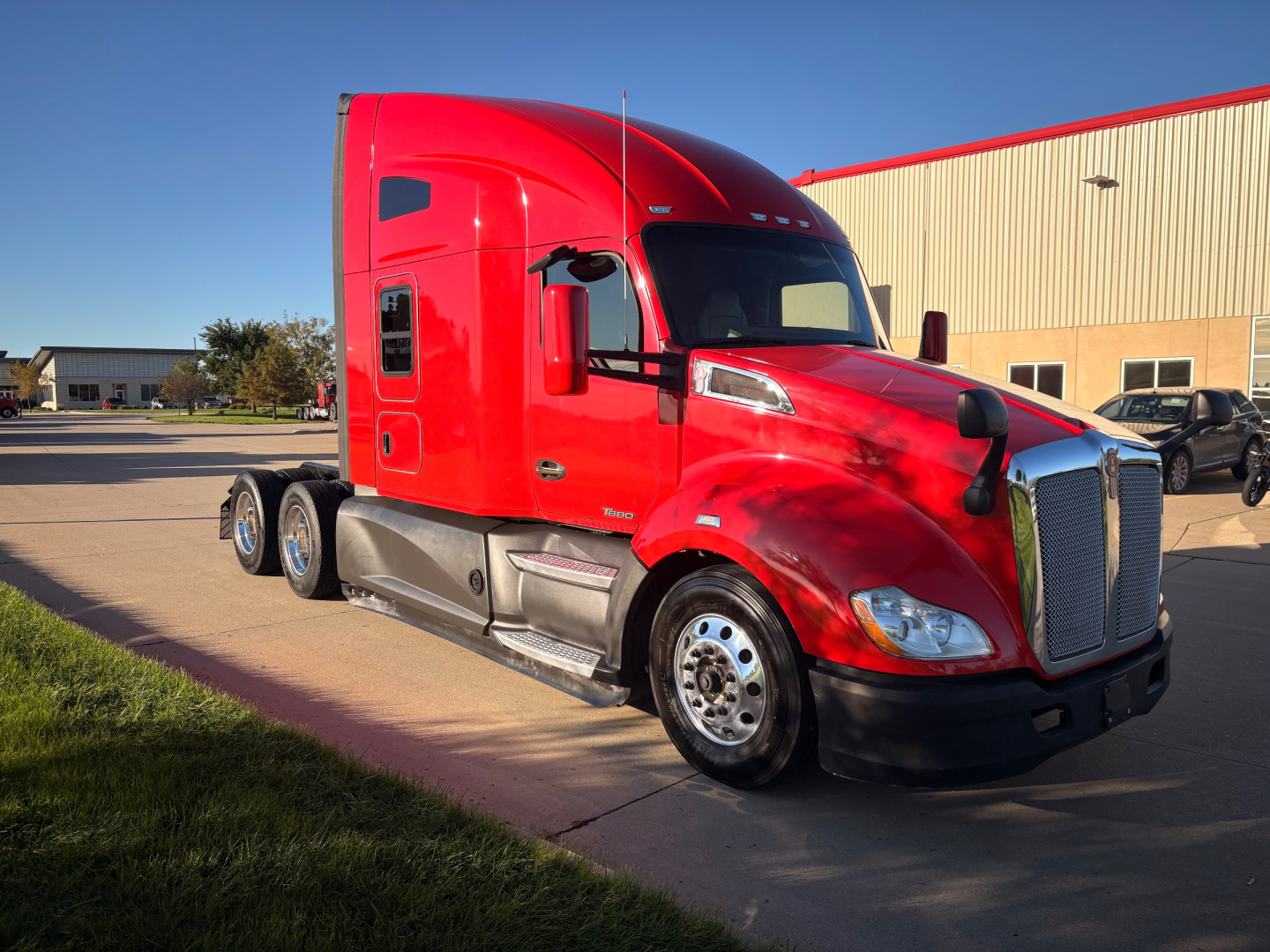 Kenworth T680 truck side view showing bright red exterior and sleeper cab.