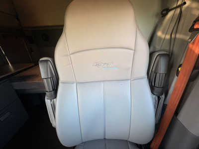 Kenworth T680 truck interior seat with light gray leather, logo on headrest area.