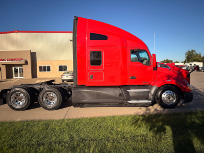 Kenworth T680 conventional sleeper truck side profile, red cab, black chassis, chrome wheels, daytime outdoor lot.