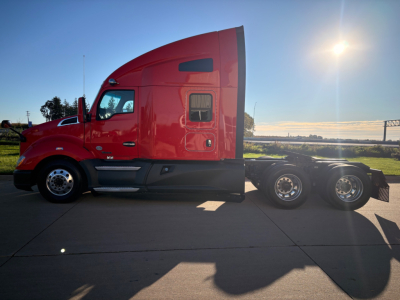 Kenworth T680 tractor side view showing red sleeper cab and rear axles, no text visible on the vehicle