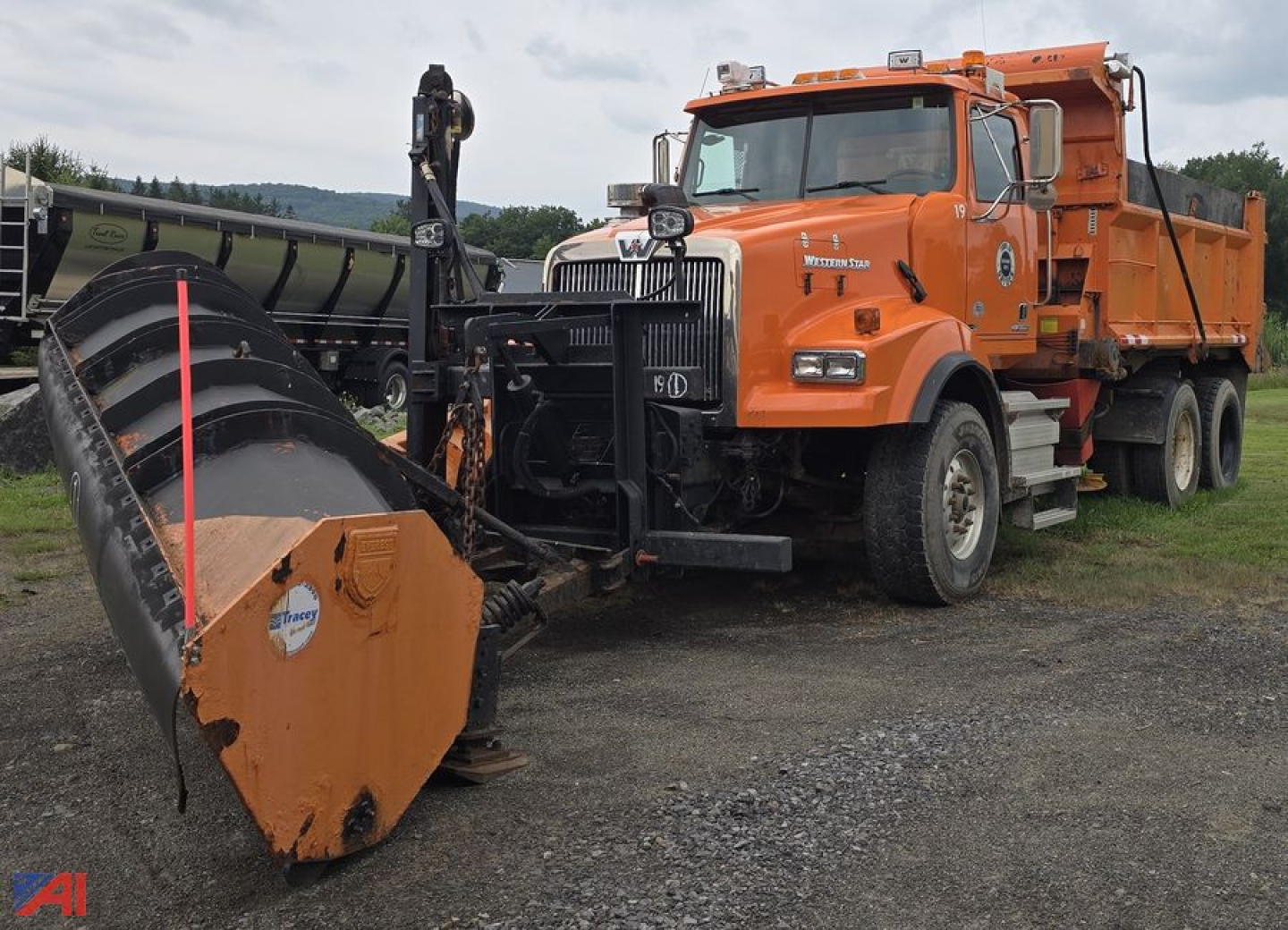 Orange 2012 Western Star 4900 SB dump truck with front plow and equipment, side view, in field