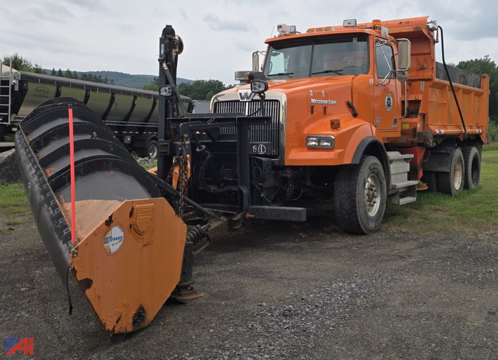 Orange 2012 Western Star 4900 SB dump truck with front plow and equipment, side view, in field