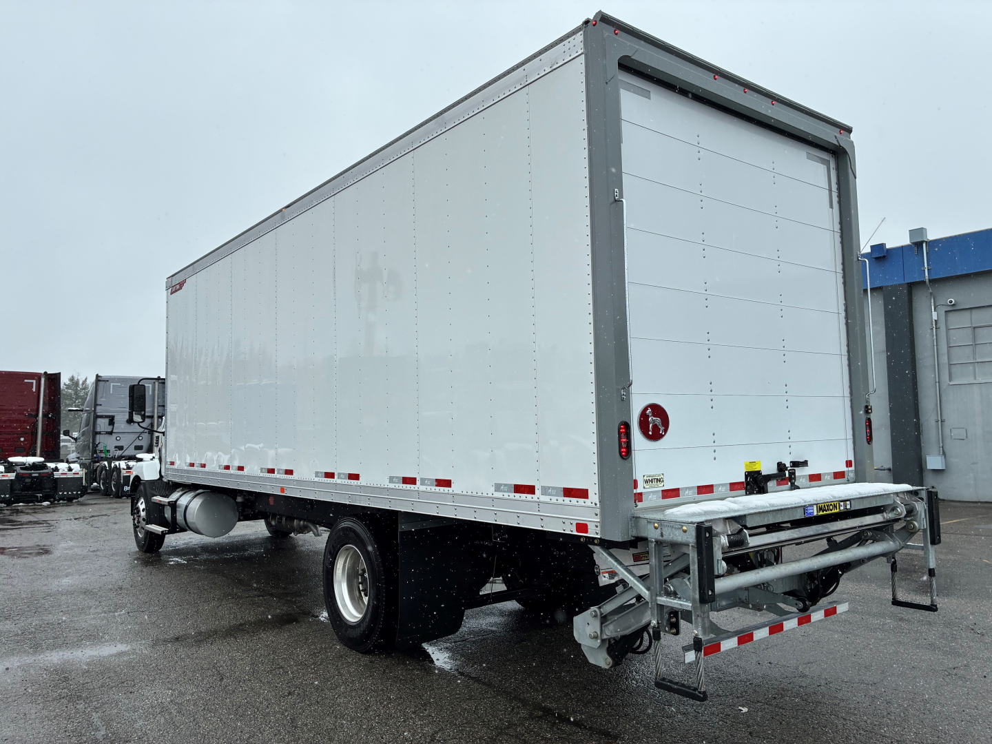 Box truck with rear ramp and grey cargo trailer showing plain white panels and chrome bumper.