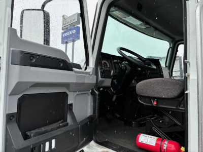 Cab interior of a 2025 Mack MD6 truck with open door, steering wheel, seat, and dashboard visible.