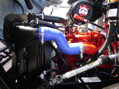 Mack MD6 engine bay showing blue coolant hose, red engine, radiator, and various hoses and clamps.
