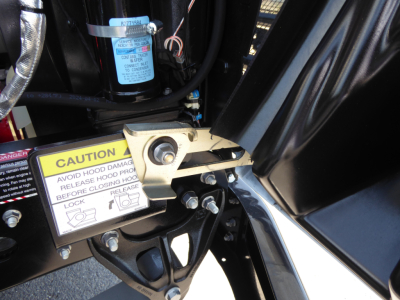 Mack MD6 engine bay area showing caution label, hydraulic hose, and blue filter near black metal framework.