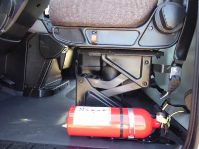 Interior of a Mack MD6 cab showing under-seat area with a red fire extinguisher attached to a bracket.