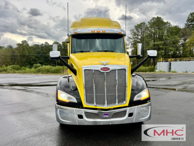 Peterbilt 579 conventional sleeper front view in yellow and black, chrome grille, headlights on, MHC Longview logo watermark.