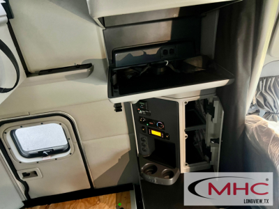 Peterbilt truck interior showing a control panel with power outlets, switches, and a small open compartment; MHC Longview logo bottom-right.