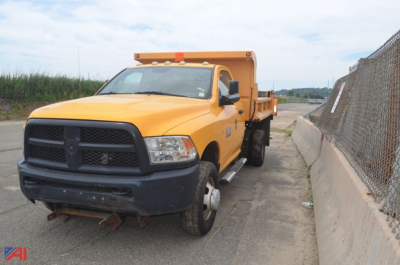 Yellow Ram 3500 dump truck in service bay showing front grille and rear dump bed.
