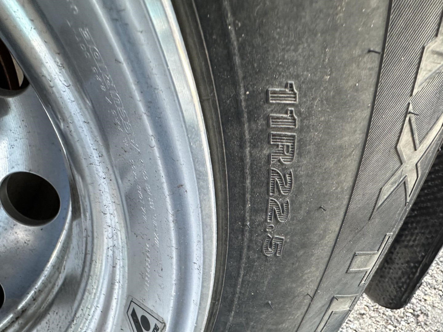 Tire sidewall with markings including 12R22.5 or similar size code visible on a trailer wheel.