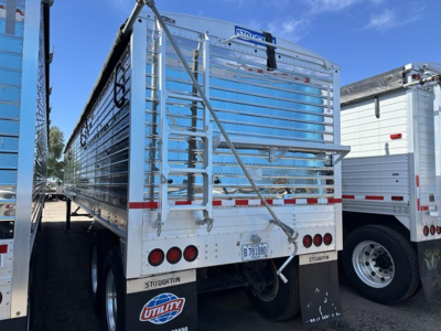 Stoughton grain trailer in side view showing rear tailgate and ladders with reflective tape and utility plate.