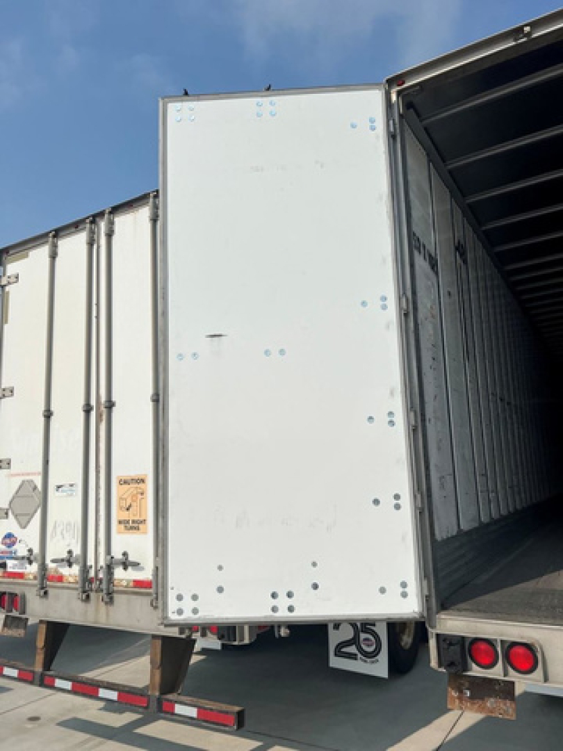 Trailer rear door and open van compartment showing interior cargo area with exposed framework and rear lighting.