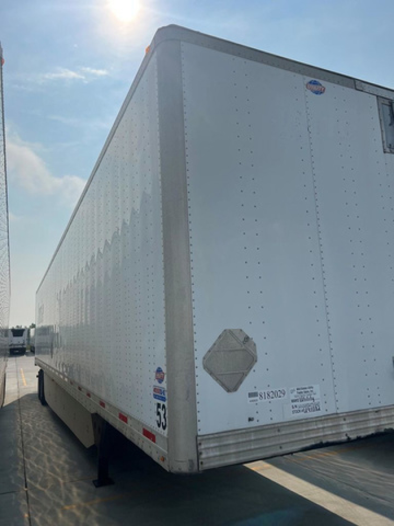 Utility van trailer side view showing riveted aluminum exterior and rear corner, no cab visible.