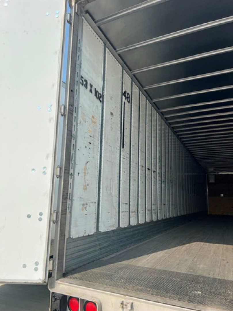 Utility van trailer interior showing empty cargo space with vertical ribbed walls and rear doorway