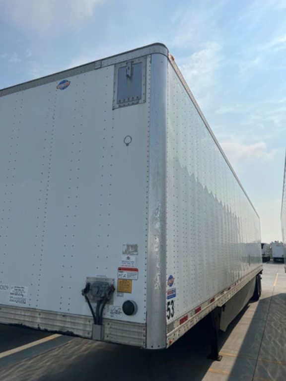 Utility van trailer side showing rear corner with reflective riveted panels and identification decals.