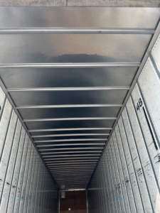 Trailer interior showing metal walls and ceiling ribs of a cargo trailer with numbered side markings.