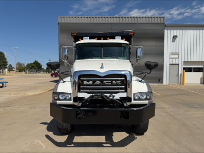 Front view of a white 2023 Mack GR84F dump truck showing large bumper and grille with Mack letters.