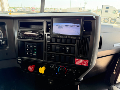Truck cab dashboard of 2023 Mack GR84F showing multimedia monitor, climate controls, gear selector, and control switches.