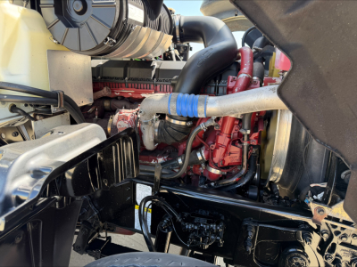Mack GR84F engine bay showing red engine components, hoses, and surrounding black chassis.