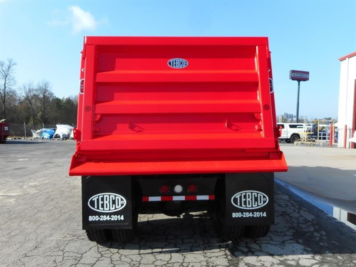Dump truck bed of a new 2027 Western Star 47X showing TEBCO rear mud flaps and red dump body.
