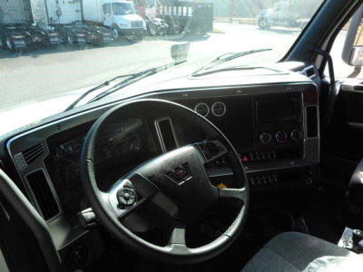 Cab interior of a Western Star truck showing steering wheel, dashboard with gauges, and infotainment screen.