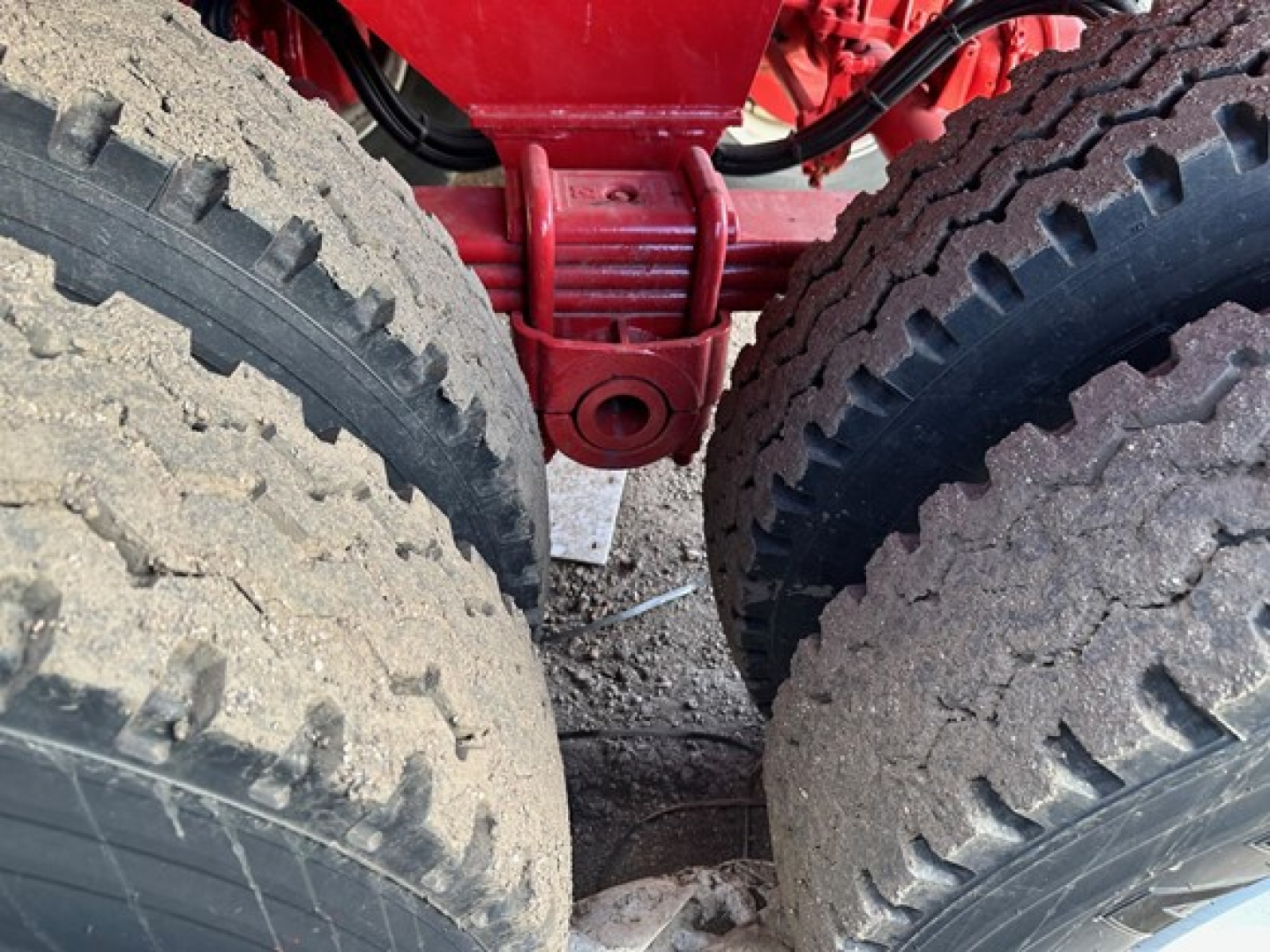 Truck trailer hitch area with dual rear tires and red suspension/u-bolts visible in a rock end dump trailer.