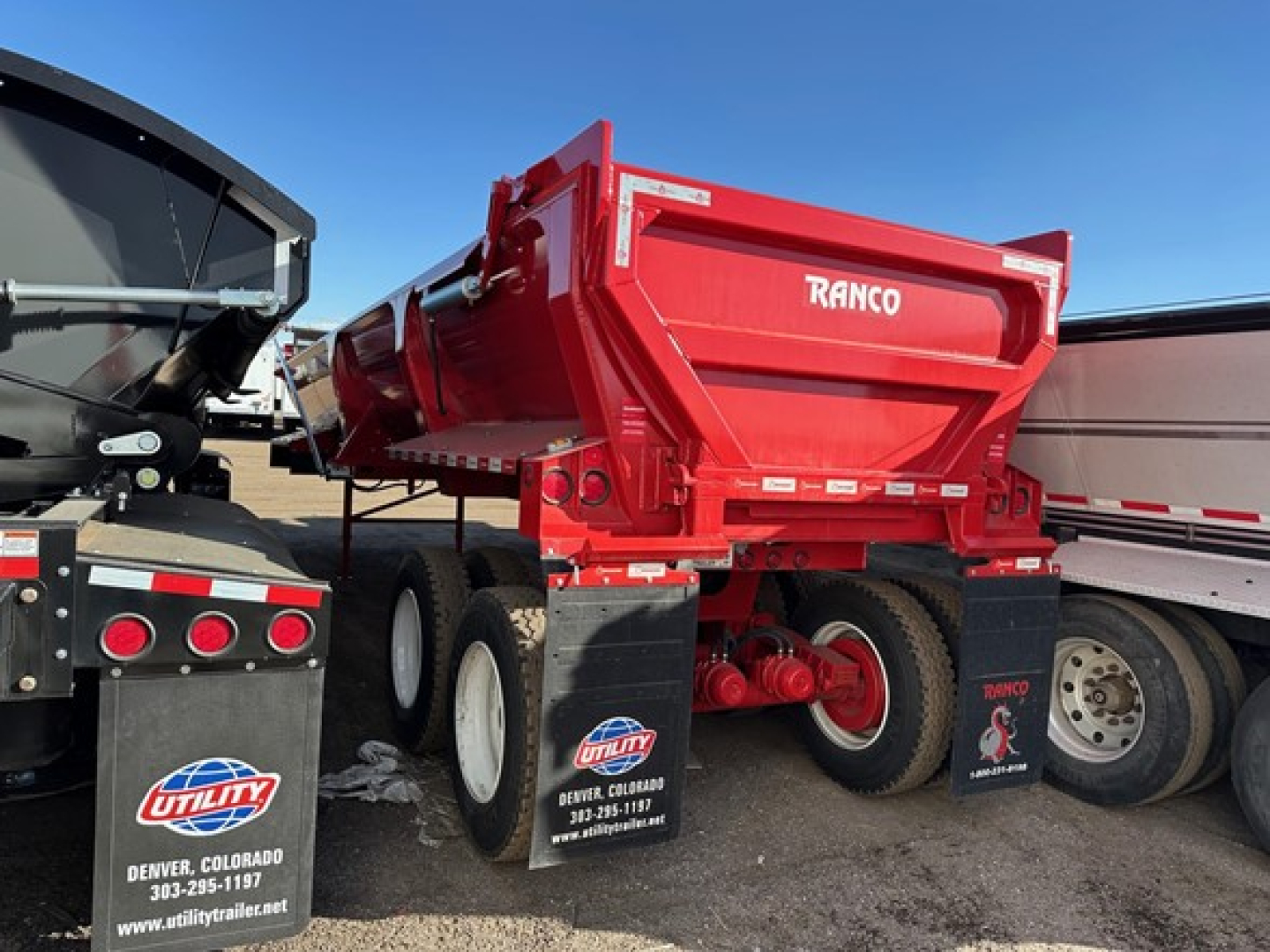 Ranco rock end dump trailer in red, rear view showing dump bed and dual tires, with 'RANCO' logo on tailgate.