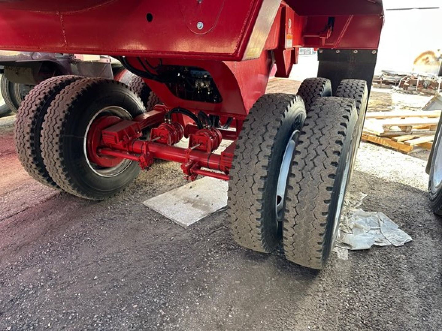 Red Ranco Rock End Dump trailer undercarriage showing dual rear axles with heavy-duty tires and red chassis components.